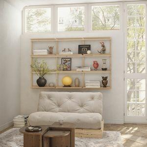 Sfeervolle woonkamer met Karup Design slaapbank Flip (off-white futon, FSC-dennenhouten boxframe) voor open wandrek vol boeken en decor.