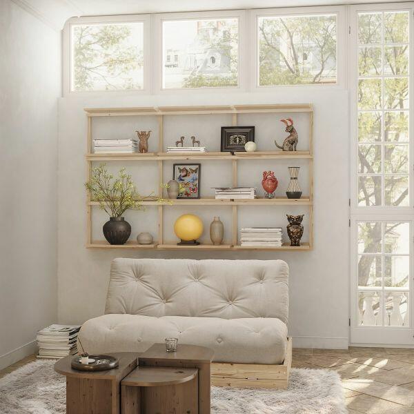 Sfeervolle woonkamer met Karup Design slaapbank Flip (off-white futon, FSC-dennenhouten boxframe) voor open wandrek vol boeken en decor.
